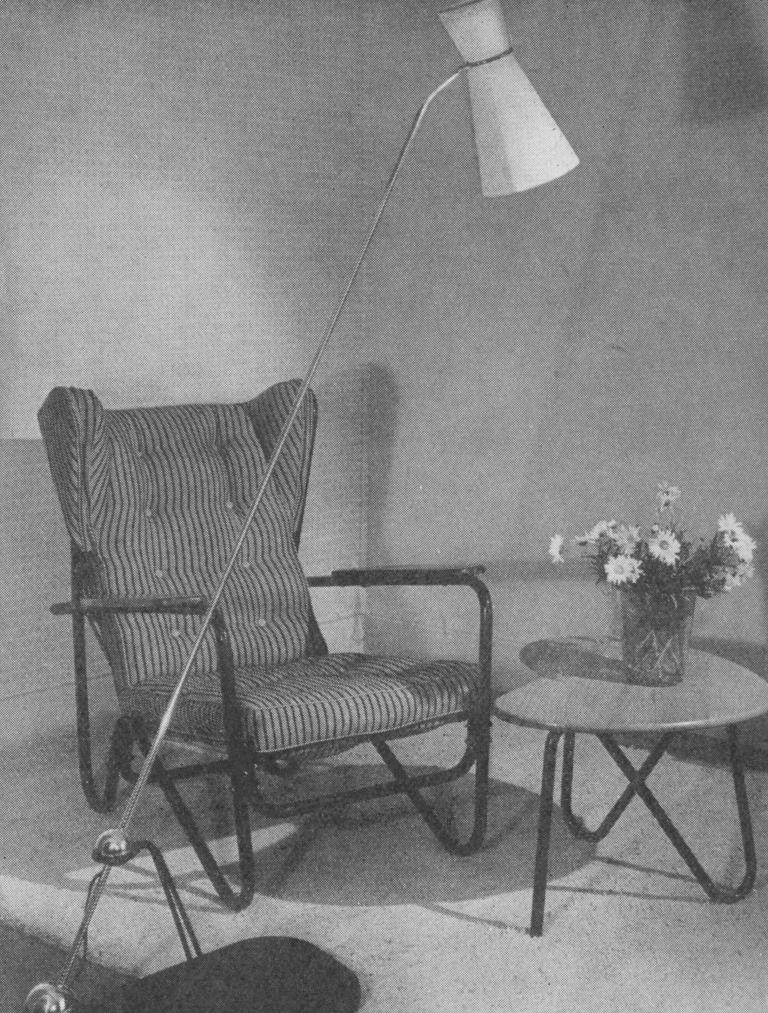 Black and white archival image of the Prefacto chair by Pierre Guariche, presented with a floor lamp and side table, c. 1950